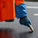 ASF Viertel RoadCare team member clearing debris from a road after an accident, with safety vests and gloves.